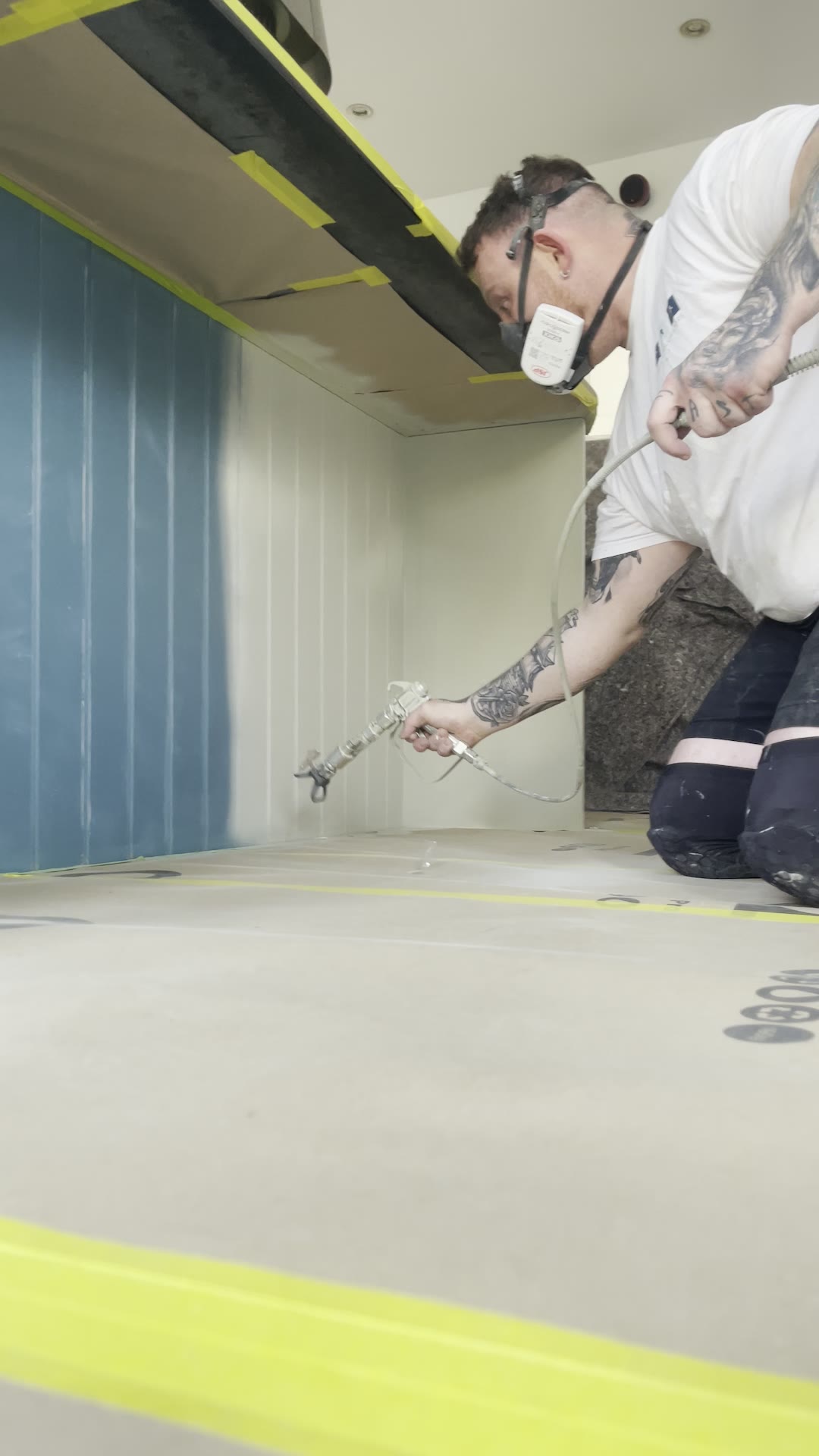 Professional sprayer applying Renner water-based coating to a kitchen island