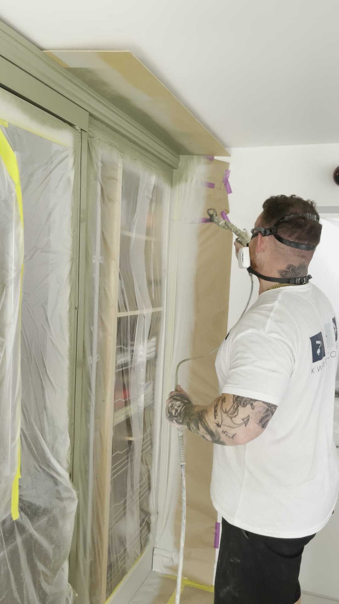 Sprayer refinishing a tall fitted unit in an occupied home
